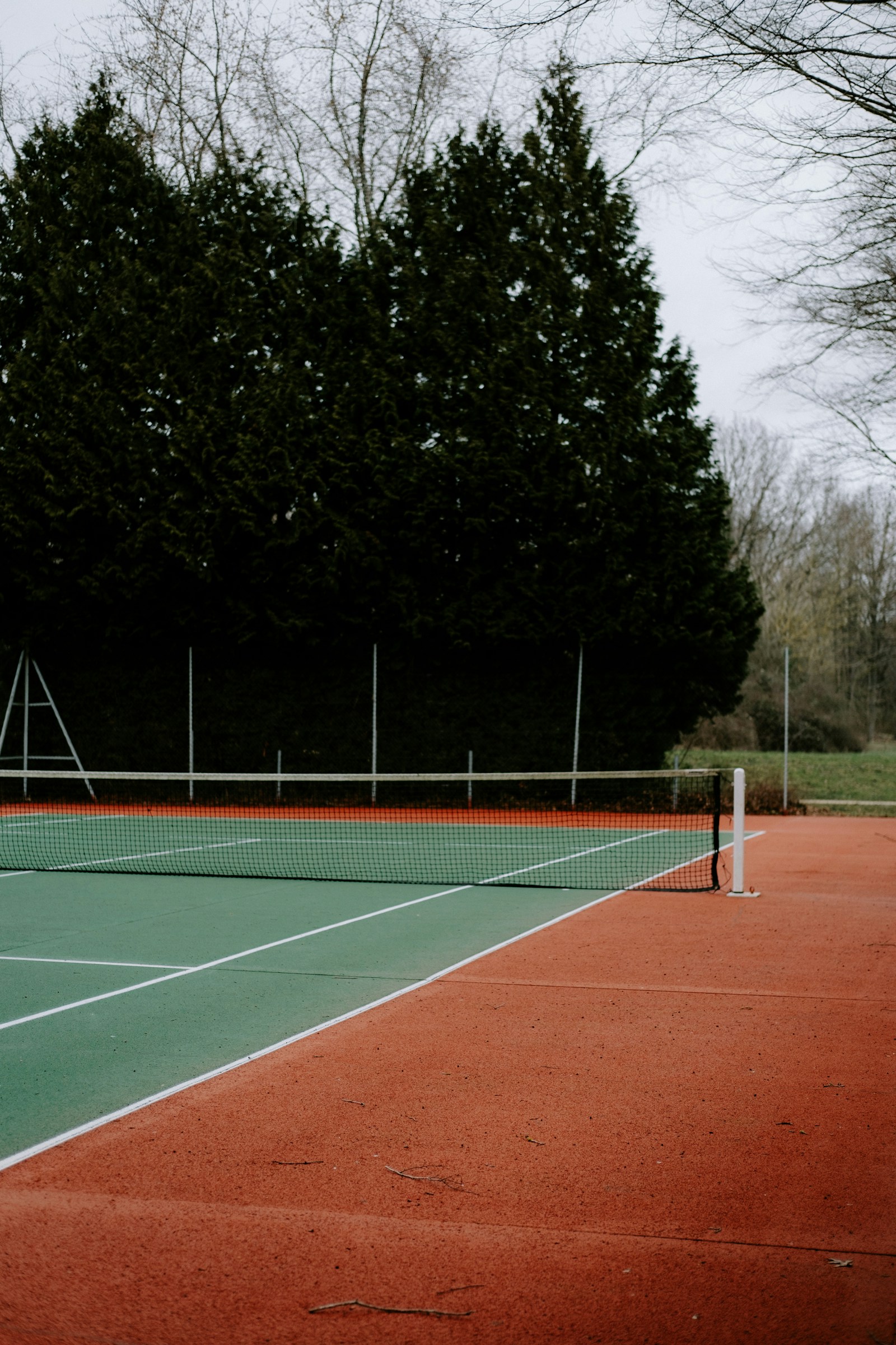 A real outdoor tennis court with its net and trees beyond